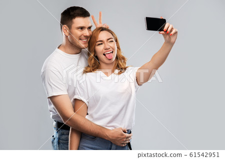 happy couple in white t-shirts taking selfie 61542951