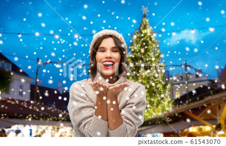 woman in hat sending air kiss at christmas market 61543070