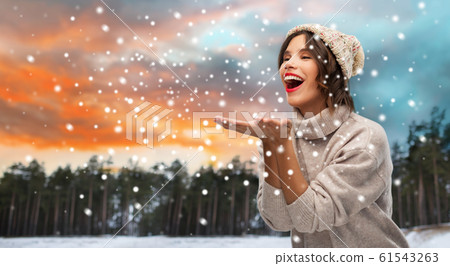 woman in hat sending air kiss over winter forest 61543263
