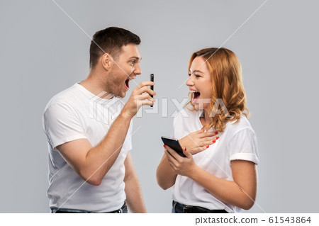 happy couple in white t-shirts with smartphones 61543864