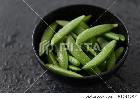 peas in bowl on wet slate stone background 61544507