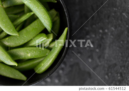 peas in bowl on wet slate stone background 61544512