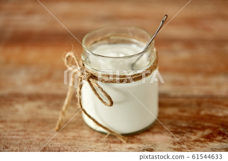 yogurt or sour cream in glass jar on wooden table 61544633