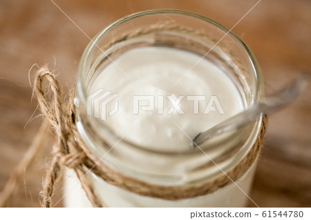 yogurt or sour cream in glass jar on wooden table 61544780