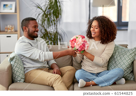 happy couple with bunch of flowers at home happy couple with bunch of flowers at home 61544825