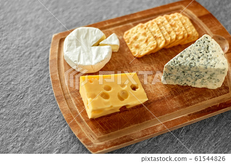 different cheeses and crackers on wooden board 61544826