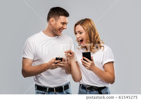 happy couple in white t-shirts with smartphones happy couple in white t-shirts with smartphones 61545275