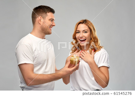happy couple in white t-shirts with christmas gift happy couple in white t-shirts with christmas gift 61545276