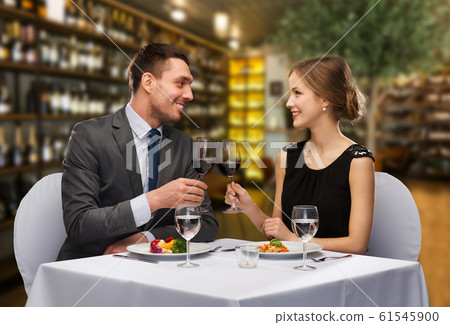 smiling couple clinking wine glasses at restaurant 61545900