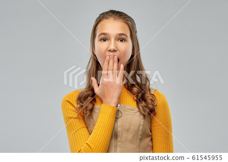 teenage girl closing her mouth by hand or yawning teenage girl closing her mouth by hand or yawning 61545955