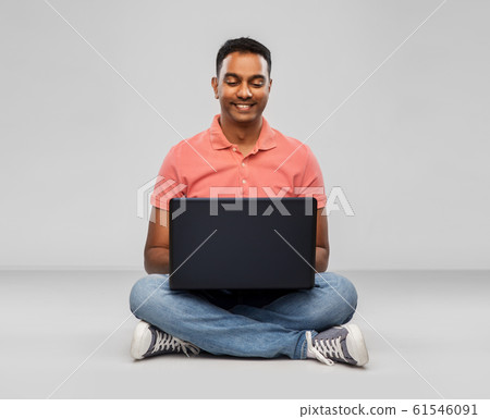 happy indian man with laptop computer on floor 61546091