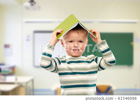 smiling boy with book on head at school 61546098