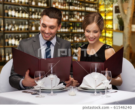 smiling couple with menus at restaurant 61546240
