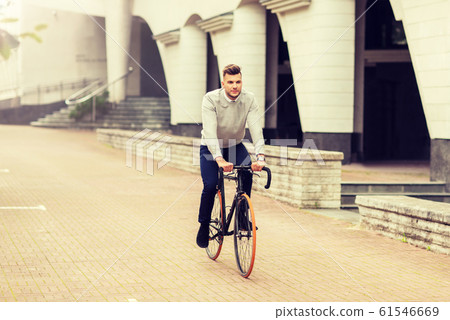 young man riding bicycle on city street young man riding bicycle on city street 61546669