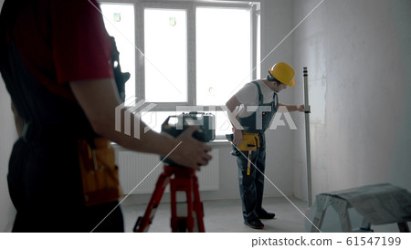 Repairing on the draft apartment - two men workers working indoors Repairing on the draft apartment - two men workers working indoors 61547199