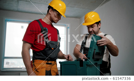 Two men workers pulling instruments out of the case Two men workers pulling instruments out of the case 61547336