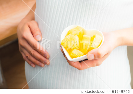 Pineapple pregnant woman cut fruit Pineapple pregnant woman cut fruit 61549745