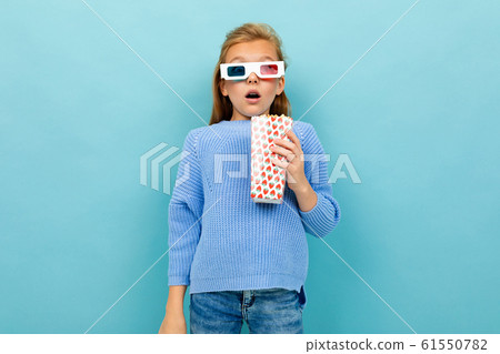 A girl with makeup and long brown hair, 3d glasses looks film or cartoon with popcorn 61550782