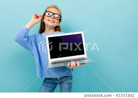 Charming caucasian girl works or studies with laptop and shows it isolated on blue background 61551882