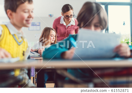 Teacher checking results of a written test in class talking to the pupils 61552871