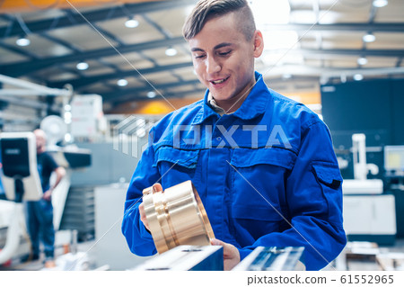 Apprentice in metalworking looking at workpiece 61552965