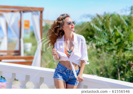A young woman model in denim clothes near a white stone low fence A young woman model in denim clothes near a white stone low fence 61556546