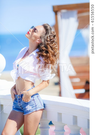 young beautiful woman in clothes near the resort wearing sunglasses while on vacation young beautiful woman in clothes near the resort wearing sunglasses while on vacation 61556550