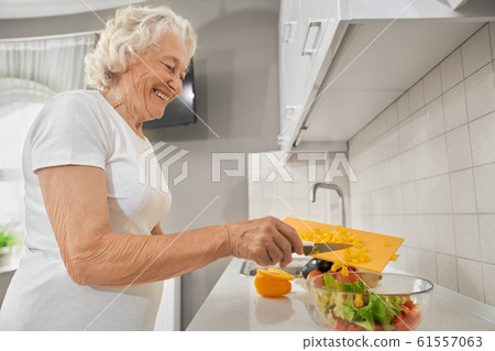 Senior woman making salad in kitchen. 61557063
