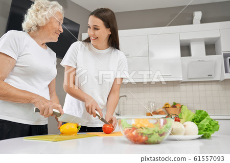 Senior woman cooking salad with granddaughter. Senior woman cooking salad with granddaughter. 61557093