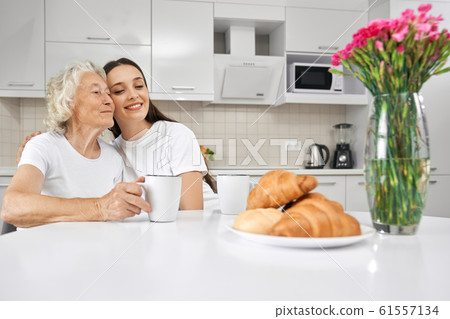 Young girl hugging grandmother in kitchen. 61557134
