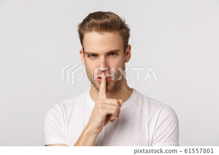 Close-up studio portrait blond handsome, sassy bearded guy squinting displeased, look strict and bossy, shushing, press index finger to lip telling be quiet, stay silent, keep secret, hushing 61557801