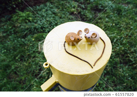 Two wooden mice couple sitting on a metal yellow round cylinder 61557820