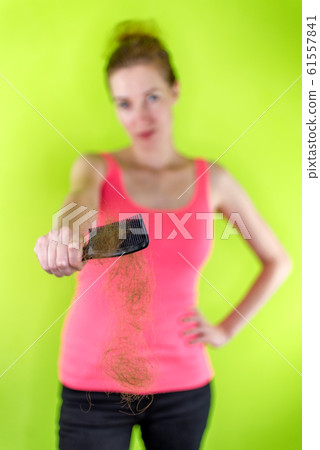Woman holding comb full of brown hair. 61557841