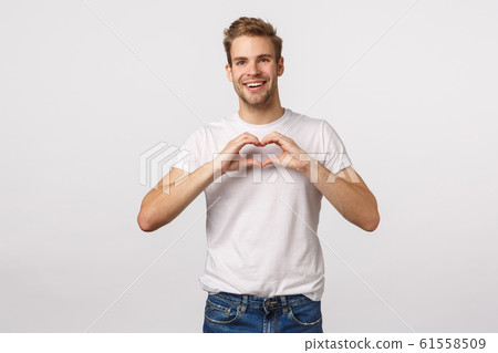 Dreamy and cute lovely boyfriend want make girlfriend surprise, confess, sharing his affection and positive emotions, make heart gesture near chest and smiling tender, white background 61558509