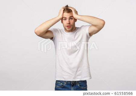 Alarmed and frustrated, blond guy in panic, grab head and stare camera speechless, feeling nervous, dont know what do, standing indecisive, have problems, posing troubled white background 61558566