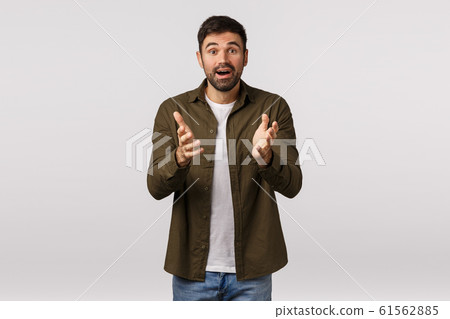 Cheerful and relieved happy surprised young kind bearded man, describe his impressions and amazement, gesturing with hands as having conversation, smiling joyful, standing white background 61562885