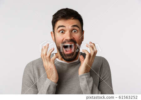 Excited, cheerful and upbeat good-looking bearded man in grey sweater, hear amazing news, shaking hands near face and shouting astonished, winning, receive prize, achieve goal, white background Excited, cheerful and upbeat good-looking bearded man in grey sweater, hear amazing news, shaking hands near face and shouting astonished, winning, receive prize, achieve goal, white background 61563252