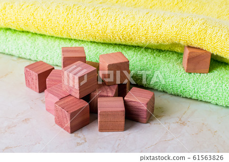 Scented wooden cubes near two bath towels. Cedar wood cubes as eco friendly wardrobe freshener. Scented wooden cubes near two bath towels. Cedar wood cubes as eco friendly wardrobe freshener. 61563826