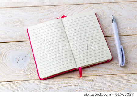 Opened lined paper notebook in a pink cover and white ballpoint pen on a white wood textured surface Opened lined paper notebook in a pink cover and white ballpoint pen on a white wood textured surface 61563827