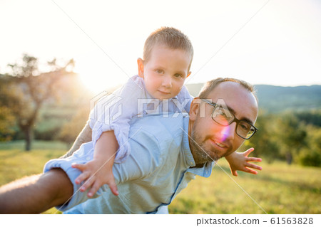 Father with small toddler son on walk on meadow outdoors, having fun. Father with small toddler son on walk on meadow outdoors, having fun. 61563828