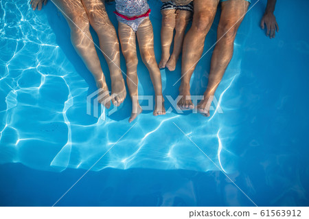 Midsection of family with small children sitting in swimming pool outdoors. Midsection of family with small children sitting in swimming pool outdoors. 61563912
