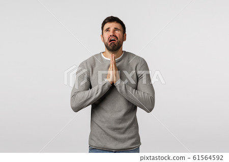 Miserable and distressed young pathetic bearded guy asking mercy, praying god hear prayers, hold hands together over chest, crying and complaining unfair life, want wish come true, white background 61564592