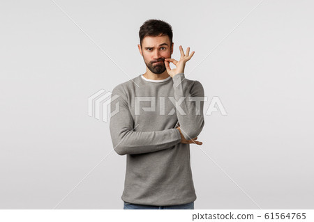 I am numb as fish. Handsome bearded gay man, office worker gossiping coworker, make zip gesture as if secure lips with key not tell anyone, promise keep shut, hide secret, standing white background 61564765