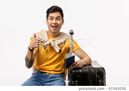 Carefree, relaxed happy chinese man travelling, sitting with black suitcase, show thumb-up pleased, recommend travel agency, trip planner or booking app, found excellent hotel where stay vacation Carefree, relaxed happy chinese man travelling, sitting with black suitcase, show thumb-up pleased, recommend travel agency, trip planner or booking app, found excellent hotel where stay vacation 61565030