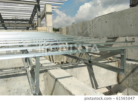 Lightweight roof trusses under construction at the construction site. Installed properly by workers to received the roof covering system.  61565847
