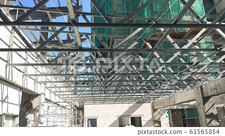 Lightweight roof trusses under construction at the construction site. Installed properly by workers to received the roof covering system.  61565854