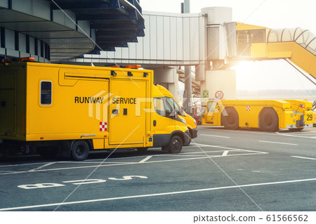 Runway service vehicles standing on tarmac near airport terminal building. Special maintenance crew truck van and tow tractor parked at marked place parking. Emergency and support equipment airfield Runway service vehicles standing on tarmac near airport terminal building. Special maintenance crew truck van and tow tractor parked at marked place parking. Emergency and support equipment airfield 61566562