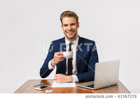 Cheers. Pleasant successful, good-looking businessman with blond hair, beard, sitting office, raise coffee cup and smiling talking to business partner, coworkers, working with laptop and documents 61567278
