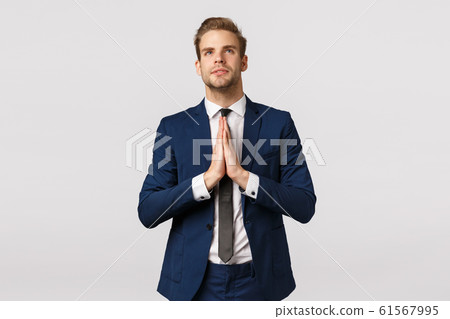 Hopeful attractive blond caucasian guy, male entrepreneur in classic suit, business formal wear, hold hands together in pray, look up sky like believer, praying, making wish, white background Hopeful attractive blond caucasian guy, male entrepreneur in classic suit, business formal wear, hold hands together in pray, look up sky like believer, praying, making wish, white background 61567995