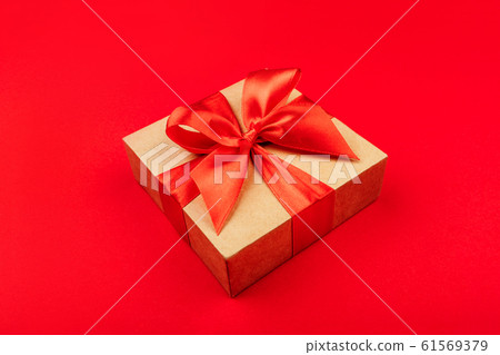 Cardboard gift box with bow on red background. 61569379